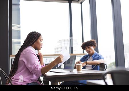 Eine junge Frau und ein Mann arbeiten in einem modernen Geschäftsbüro zusammen und halten ein Tablet in der Hand Stockfoto