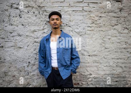 Gutaussehender Kerl, der auf einer Mauer steht und in die Kamera schaut. Stockfoto