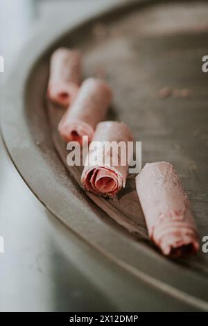 Nahaufnahme von Erdbeereis-Rollen auf gefrorenem Metallmaschinenoberteil Stockfoto