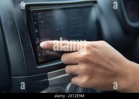 Mit dem Finger die Lautstärke eines Autoradios erhöhen. Transportkonzept. Stockfoto
