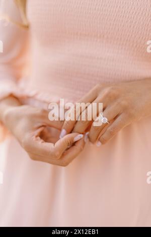 Runder Verlobungsring an der Hand der Frau in rosa Kleid Stockfoto