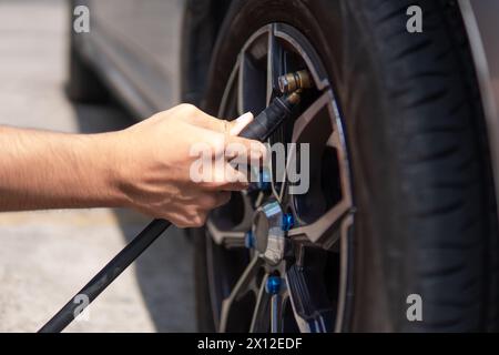 Nahaufnahme eines Mannes, der Reifen aufbläst, Luft in die Reifen seines Autos einfüllt. Stockfoto