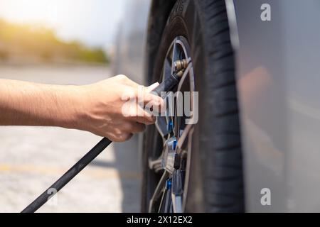 Nahaufnahme eines Mannes, der Reifen aufbläst, Luft in die Reifen seines Autos einfüllt. Stockfoto