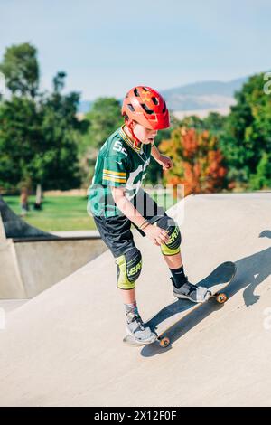 Junge mit rotem Helm, der im Skatepark läuft Stockfoto