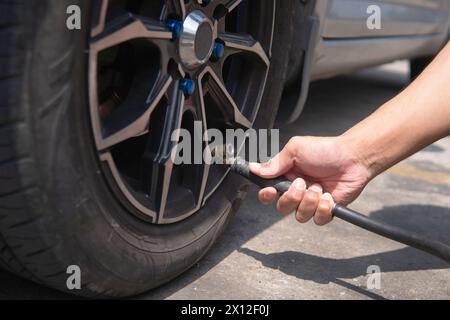 Nahaufnahme eines Mannes, der Reifen aufbläst, Luft in die Reifen seines Autos einfüllt. Stockfoto