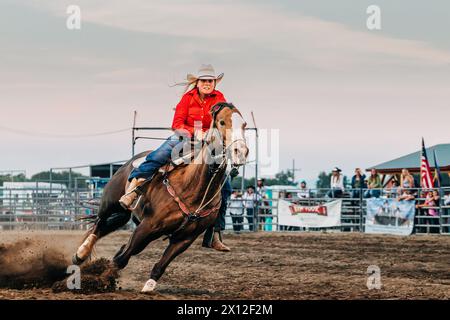 Cowgirl reitet auf einem Pferd während eines Fass-Rennens beim Rodeo der County Fair Stockfoto