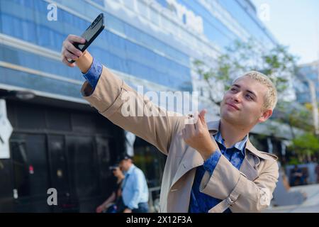 Junger lateinamerikanischer argentinischer Mann, hübscher blonder Unternehmer in formeller Kleidung, der im Freien Selfie-Foto mit seinem Handy macht Stockfoto