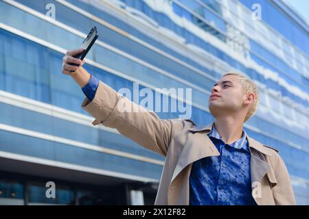 Junger lateinamerikanischer argentinischer Mann, hübscher blonder Unternehmer in formeller Kleidung, der im Freien Selfie-Foto mit seinem Handy macht Stockfoto
