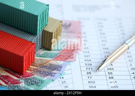 Globale Business Container Frachtschiff in Import Export Business Logistik. Firmenversand und Logistik in Indonesien mit Rupiah-Geldrechnungen und Pen-Nahaufnahme Stockfoto