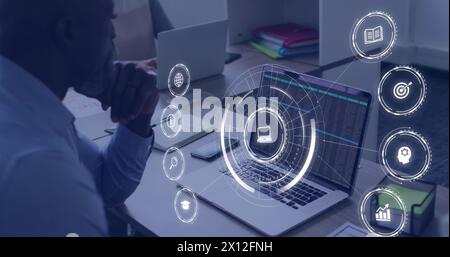 Bild von herabfallenden Bildungsikonen über afroamerikanischen Männern mit Laptop Stockfoto