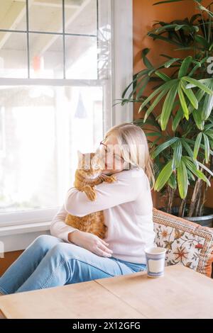 Frau, die ihre Ingwerkatze liebevoll umschließt Stockfoto