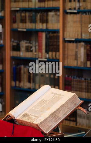 Ein einziges altes Buch wurde vor Bücherregalen geöffnet Stockfoto