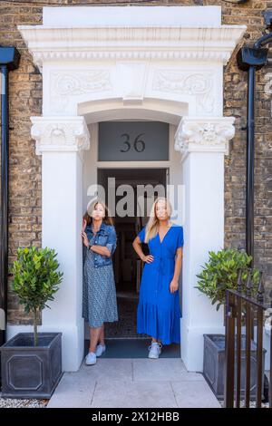 Zwei Freunde stehen vor der Tür zur Londoner Wohnung, Großbritannien Stockfoto