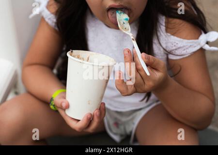 Mädchen isst Eis mit Löffel Stockfoto