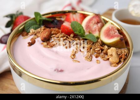 Schüssel mit Joghurt, Obst und Müsli auf weißem Tisch, Nahaufnahme Stockfoto