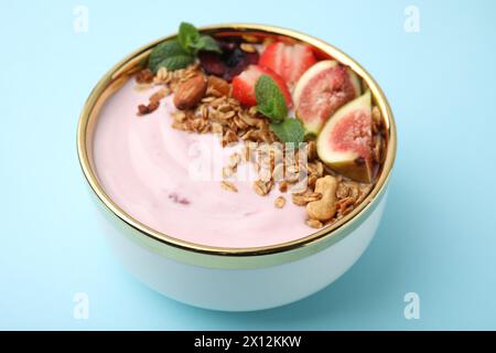 Schüssel mit Joghurt, Obst und Müsli auf hellblauem Hintergrund, Nahaufnahme Stockfoto