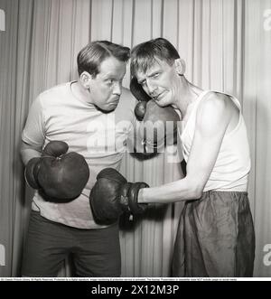 Boxning lustig die beiden Revue-Schauspieler in ihrer Bühnenkleidung fangen in dem Moment auf der Bühne ein, in dem sie sich mit Boxhandschuhen und Schlägen gegenüberstehen. Carl-Gustaf Lindstedt. 1921-1992. Schwedischer Schauspieler. Hier links in Scalateaterns Revue 'Här håller VI hus' 1952. Auf der rechten Seite Curt Löwgren. 1908-1966. Kristoffersson Ref. BH36-9 Stockfoto