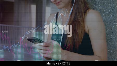 Bild von Diagrammen, Zahlen, Handelstafel, kaukasierin, die Musik hört und Handy benutzt Stockfoto