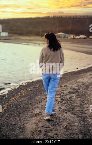 49 Jahre alte russische Frau, die in Richtung Sonnenuntergang in der Nähe des japanischen Meeres geht Stockfoto