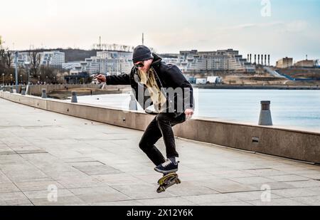 Junger Mann, der auf einem Skateboard fährt und Tricks und Sprünge macht Stockfoto