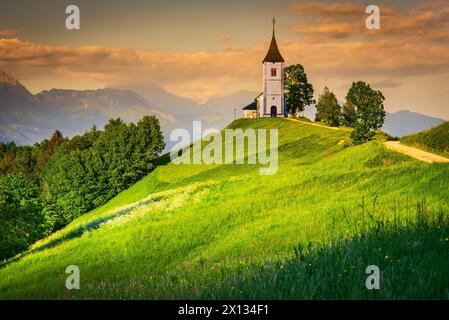 Jamnik, Slowenien - berühmte mittelalterliche Kirche St. Primus, goldenes Licht bei Sonnenuntergang. Kamnik-Savinja Alpen, Skofja Loka Stockfoto