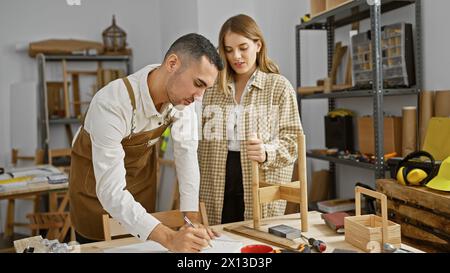 Ein Mann und eine Frau arbeiten in einer Werkstatt zusammen, umgeben von Holzwerkzeugen und -Projekten. Stockfoto