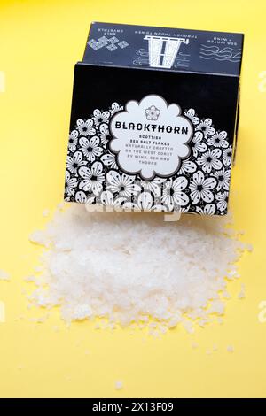 120 Gramm Blackthorn Scottish Sea Salt Flakes, die auf einem gelben Hintergrund verschüttet werden Stockfoto