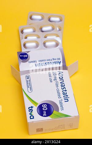 Schachtel mit 28 80 mg Atorvastatin Filmtabletten von Teva zum Einnehmen zur Behandlung von Herzproblemen und zur Senkung des Cholesterinspiegels auf gelbem Hintergrund Stockfoto