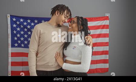 Ein Mann und eine Frau mit Aufklebern „ich habe gewählt“, die vor einer amerikanischen Flagge stehen und das Engagement der Bürger symbolisieren. Stockfoto
