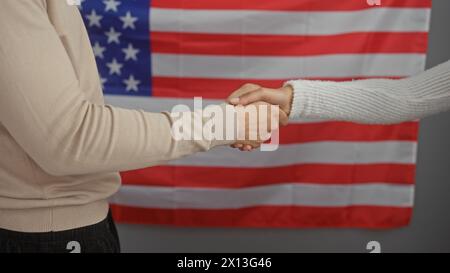 Zwei Menschen schütteln die Hand in einem Büro mit amerikanischer Flagge, das Partnerschaft und Professionalität in den usa symbolisiert. Stockfoto