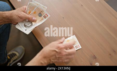 Der Mann tauscht britische Pfund auf einem Holztisch und zeigt eine Transaktion oder Zahlung drinnen. Stockfoto