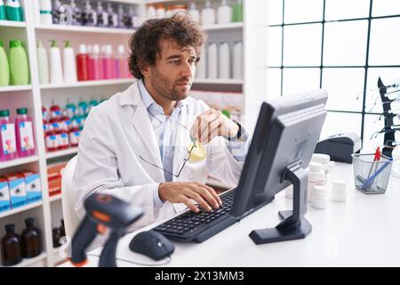 Junger hispanischer Apotheker mit Computer in der Apotheke Stockfoto