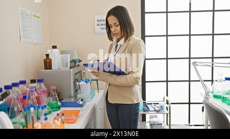 Professionelle Frau, die Dokumente in einem modernen Laborumfeld überprüft Stockfoto