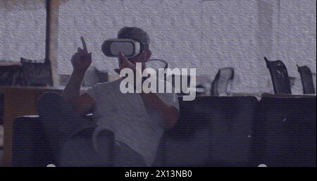 Bild eines vhs-Glitcheffekts über einem kaukasischen Mann, der vr-Headset im Büro trägt Stockfoto