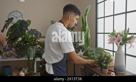 Ein Mann arrangiert Pflanzen in einem hellen Blumenladen mit Uhr und Fenster im Hintergrund Stockfoto