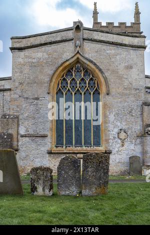 Ein großes bogenförmiges Buntglasfenster, das durch ein Drahtgeflecht geschützt wird, in der St Edwards Church, Stow on the Wold, den Cotswolds, England. Stockfoto