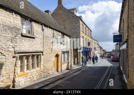 Touristen und Käufer schlendern entlang einer Straße, die von honigfarbenen Cotswold-Steinläden in Stow on the Wold gesäumt ist. Das beliebte Reiseziel der Cotswolds. Stockfoto