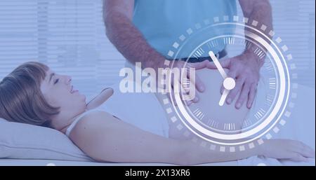 Eine schnelle Uhr über eine glückliche schwangere kaukasierin, die den Bauch vom Ehemann massiert hat Stockfoto