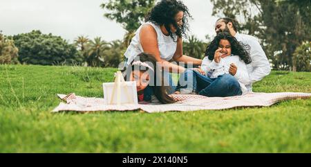 Glückliche indische Familie, die Spaß beim Malen mit Kindern und Picknicken im Stadtpark hat - Lebensstil im Frühling - Fokus auf Muttergesicht Stockfoto