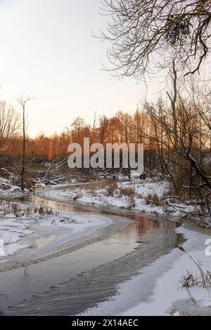 Eisbedecktes Wasser in einem Fluss im Winter, Sonnenuntergang auf einem Fluss, dessen Ufer mit Eis bedeckt sind Stockfoto