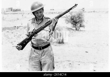 DEUTSCHE AUSRÜSTUNG VON UNSEREN PANZEREINHEITEN IN DER NÄHE VON SOLLUM - Ein britischer Soldat, der ein Gefangenes deutsches Gewehr der britischen Armee untersucht Stockfoto