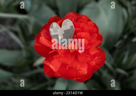 Auf der großen roten Blume liegt ein Herz aus Tarnstoff für Militäruniform. Stoppt den Krieg. Mit Liebe und Dankbarkeit den Soldaten der Streitkräfte. Stockfoto