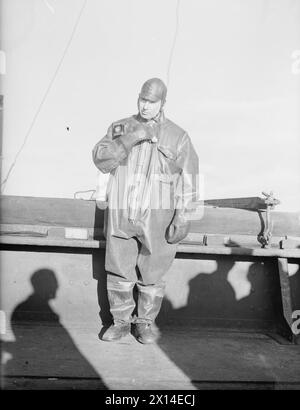 Norwegische Schiffe, die im Januar 1941 aus Göteborg flohen, werden am 25. Januar von der Home Fleet nach Kirkwall eskortiert. Captain Jensen vom Stier trägt einen lebensrettenden Anzug aus Gummi mit elektrischem Licht, der vor der Abreise an die Crew ausgehändigt wird. Stockfoto