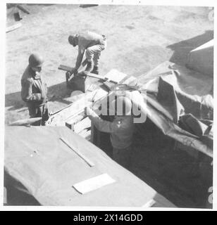 FÜNFTE ARMEE : ANZIO BRÜCKENKOPF 'BESSER 'OLES' AUF DEM ANZIO BRÜCKENKOPF - Ein 'Hundehaus' im Bau am Ende des Maulwurfs im Hafen von Anzio. Das Gerüst besteht hauptsächlich aus Treibholz, während die wasserdichte Dachverkleidung aus gummiertem Gewebe besteht, das aus einem heruntergeschossenen Stauballon abgelegt wurde. Dies ist eine von acht Hütten, die lokal "Millionaire's Row" genannt werden. PRC.John A. Grudovitch (Vordergrund) von 707 Windsor Street, McKeesport, Pa, USA, beobachtete PFC.Clarence C. Souza von Riverview Avenue, Middle Town, Box 173, Rhode Island, USA auf Bauarbeiten. während im Hintergrund Pvt.Charles Kalinick von 4796 Sek Stockfoto