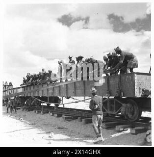 BILDER AUS DEM Western DESERTRAILWAY CONSTRUCTION - Indian Labour Corps entladen einen Wagen, der mit Schienenlängen beladen ist und in den Wagen auf dem bereits fertigen Teil der Bahn transportiert wird. Zwei der Schienen werden gegen den Wagen zum Boden gelegt, die anderen auf ihnen, wo sie zum Boden der British Army gleiten Stockfoto