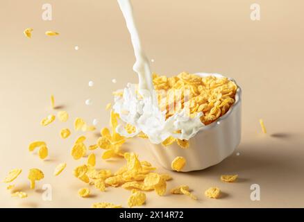 Trockene Honigmaisflocken mit Milchspritzern auf einer Keramikplatte. Flocken mit Bio-Milch. Das Konzept von gesunder Ernährung, vegetarischer und veganer Ernährung fo Stockfoto