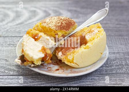 Der Leckere Gelbe Kuchen Mit Löffel Auf Der Weißen Untertasse. Süßes Essen Mit Creme Und Verschüttetem Schokoladenpulver. Stockfoto