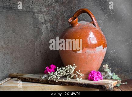 Alte Kanne neben kalanchoe-Blüten, dekorative Eukalyptuszweige und kleine weiße Blüten Stockfoto