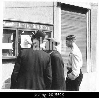 DEUTSCHE ZIVILISTEN LESEN KRIEGSENDE-PROKLAMATION - Zivilisten der Stadt Suchlten lesen die Proklamation British Army, 21st Army Group Stockfoto