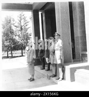 BRITISCHE TRUPPEN IN ADDIS ABEBA – italienische und britische Offiziere vor dem Gouverneurspalast und die italienische Polizei grüßen die Union Jack, als sie über die britische Armee des Palastes getrieben wird Stockfoto